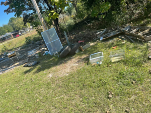 A cluttered backyard with debris, old windows, and junk ready for removal by Ty's touch junk removal,LLC in Fayetteville, NC.