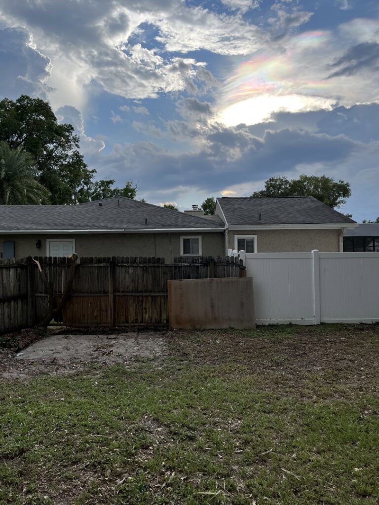 A backyard with scattered debris near a fence, indicating an area ready for junk removal by Route Junk in Orlando, FL.