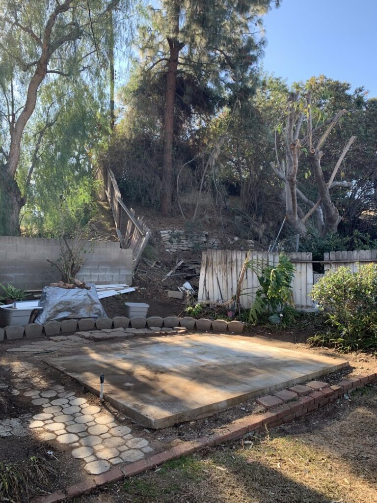 A cluttered backyard with debris and overgrown areas before junk removal by The Junk Gentlemen in Anaheim, CA.