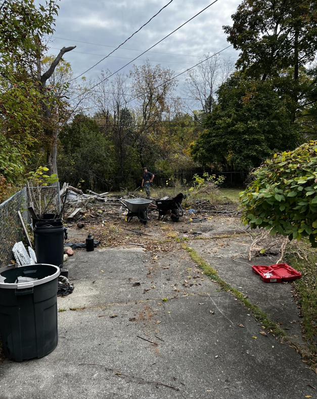 A backyard filled with debris and trash cans, showing a junk removal cleanup in progress by Junk Run 810 in Flint, MI.