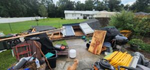 A backyard filled with debris from a collapsed shed, a grill, and other junk, ready for removal by Jax Junk Squad in Jacksonville, FL.