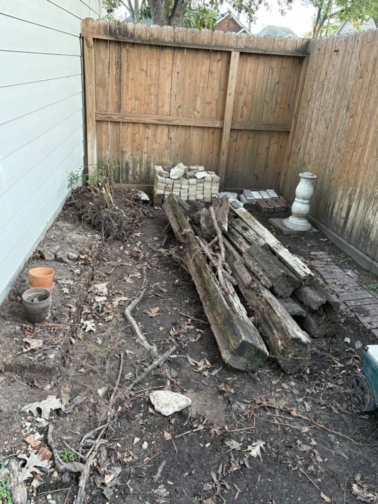 A backyard area with old wooden logs, bricks, and dirt debris, ready for Handymen Junk Removal in Houston, TX.