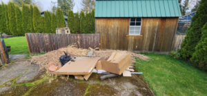 A large pile of dry reeds, cardboard, and yard debris in a backyard ready for junk removal by AG Junk Haulers in Salem, OR.