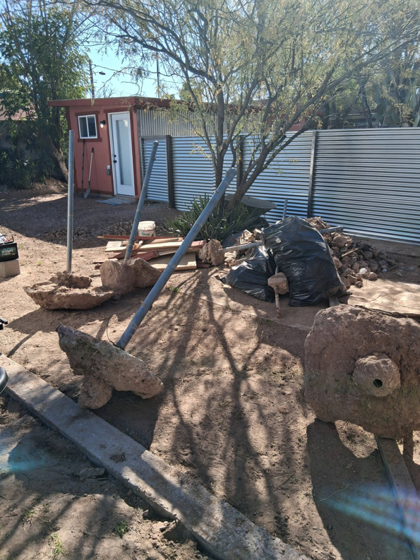 A backyard filled with construction debris, concrete, and trash bags, for Arizona Best Junk Removal & Hauling in Tucson, AZ
