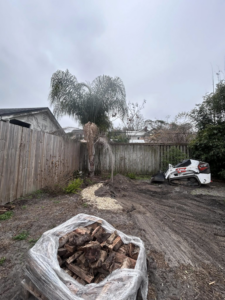 A Bobcat compact track loader and a bag of cut wood after tree service at OutReach Tree Service in Jacksonville, FL