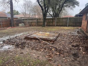 A muddy backyard with fallen leaves and a wooden structure, indicating a need for debris removal by City to City Junk Removal Fort Worth, TX.