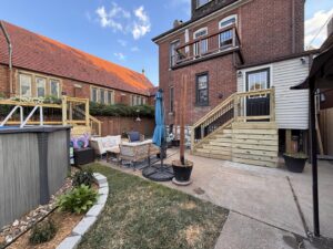 A newly constructed wooden deck with stairs leading to a backyard patio, built by McIntosh Construction in Des Peres, MO.