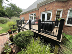 A beautiful backyard deck with black railings next to a brick house, completed by Music City Home Experience in Nashville, TN.