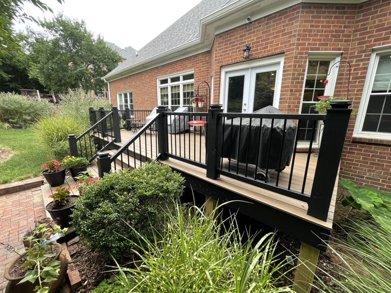 A beautiful backyard deck with black railings next to a brick house, completed by Music City Home Experience in Nashville, TN.