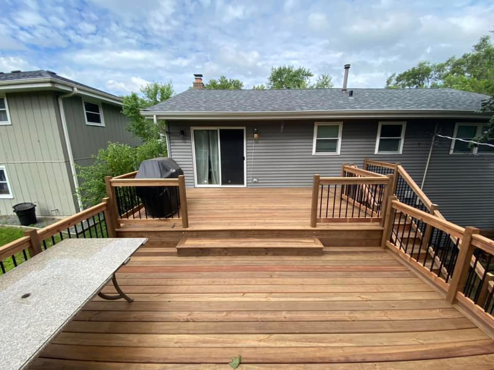 A newly installed backyard deck with dark railings and a sliding door by Strom Contracting LLC in Crystal Lake, IL.