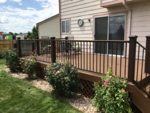 A completed backyard deck installation with black railings and surrounding landscaping by Lnk Deck & Remodels, LLC in Aurora, CO.