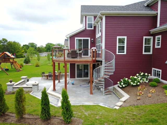A backyard featuring a custom deck, patio, fire pit, and spiral staircase installed by Screwheads Decking And Supply Store in Racine, WI