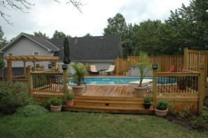 A beautifully constructed backyard deck with a swimming pool and wooden fence by Holm Remodeling Company in Kansas City, KS.