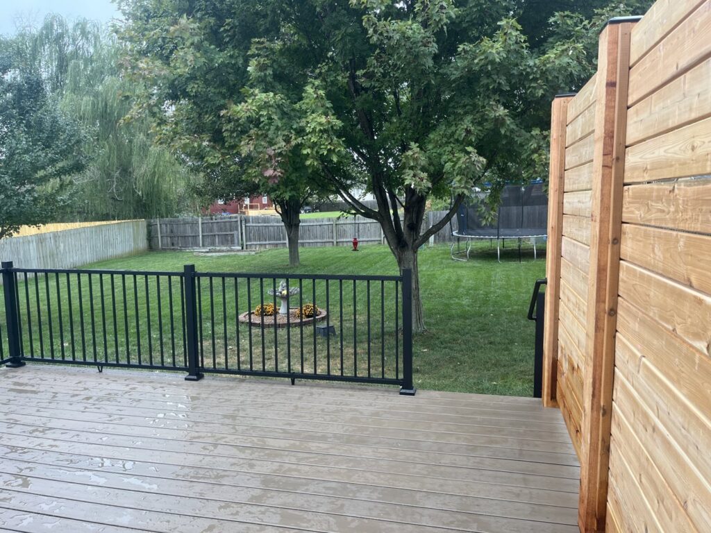 A comfortable backyard deck with a privacy screen, offering a view of the yard, built by Chad Fry the Deck Guy LLC in Blue Springs, MO.
