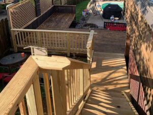 A newly constructed wooden deck in a backyard, offering a view of a swimming pool, by McIntyre's Renovations LLC in Pittsburgh, PA