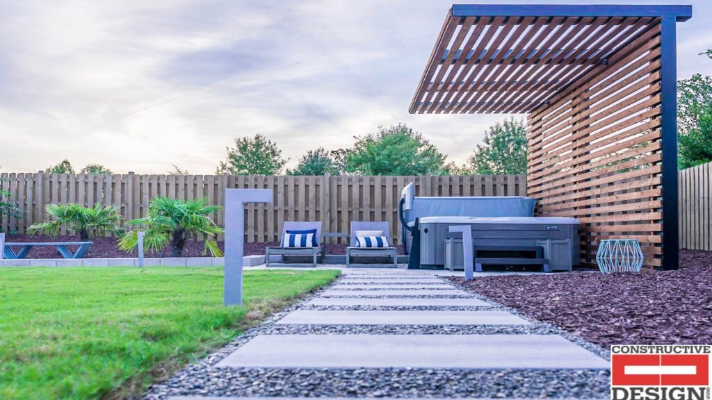 A backyard featuring a hot tub, wooden pergola, privacy fence, and stepping stones by Constructive Design Group in Raleigh, NC