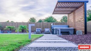 A backyard featuring a hot tub, wooden pergola, privacy fence, and stepping stones by Constructive Design Group in Raleigh, NC