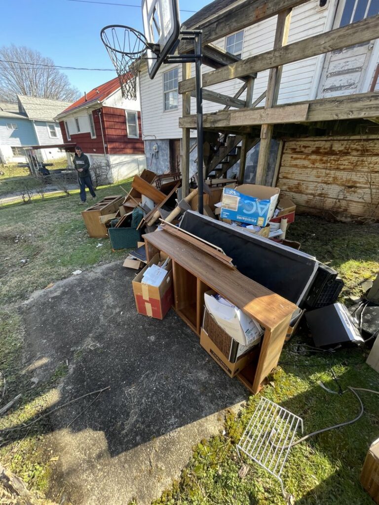 A large pile of discarded furniture, boxes, and household items in a backyard, ready for junk removal by Trash Monkey Junk Removal in Charleston, WV.