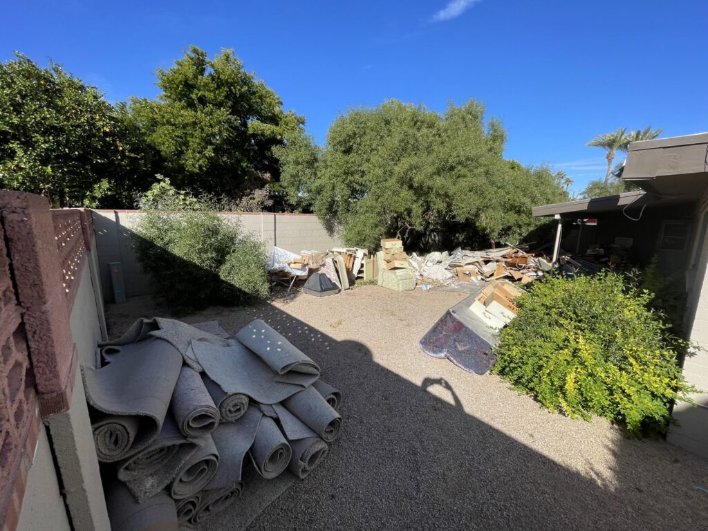 A large pile of various junk and construction debris in a backyard, awaiting removal by HAVOC Demolition in Scottsdale, AZ.