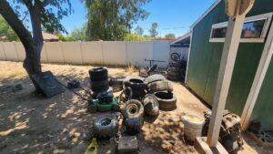 A large pile of mixed household junk and debris in a backyard, being removed by Haul-R-Us Junk Removal LLC in Fresno, CA.