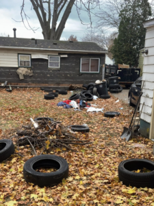 A messy backyard filled with old tires, branches, and debris, ready for general junk removal by TRS Roll-Offs LLC in Canton, OH.