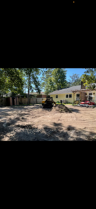 A large backyard undergoing land clearing and preparation with a skid steer loader by A and T Services LLC in North Charleston, SC.