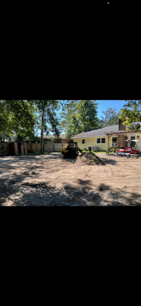 A large backyard undergoing land clearing and preparation with a skid steer loader by A and T Services LLC in North Charleston, SC.