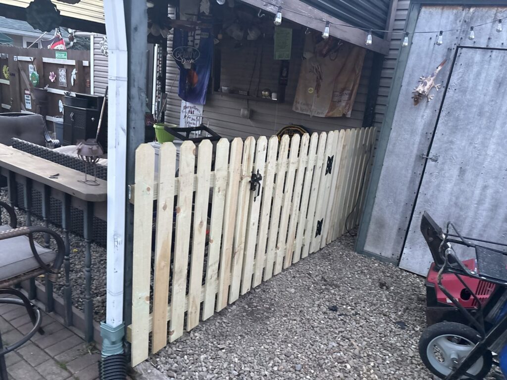 A newly installed wooden picket fence in a residential backyard by Ofandiski Fence Co. Inc in Lorain, OH.