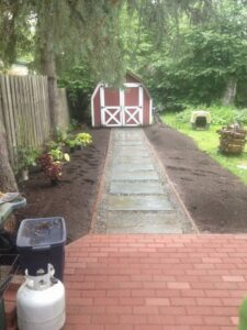 A backyard path with stepping stones and new landscaping leading to a shed, completed by Ground Up Services in Anchorage, AK.