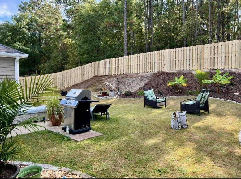 A spacious backyard patio with a newly installed wooden privacy fence by Legacy Fence, LLC in Aiken, SC.