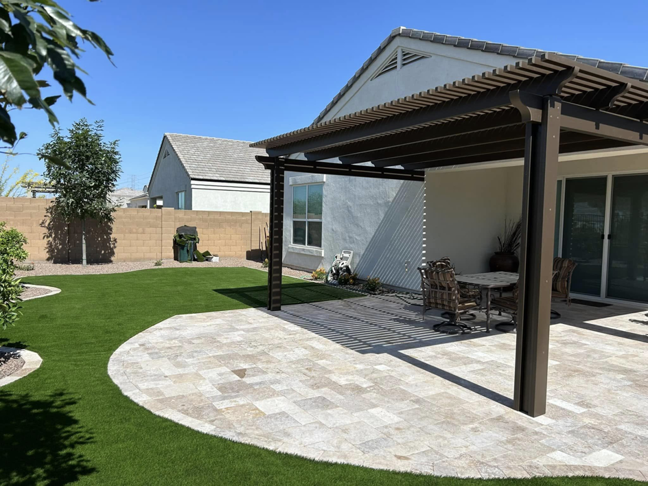 A backyard with a newly installed brown pergola and paved patio by Az Sun Covers in Glendale, AZ.
