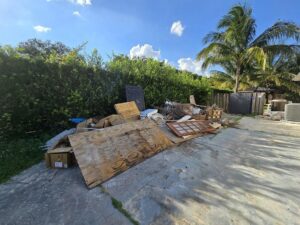 A large pile of mixed construction and household junk in a backyard, ready for removal by Junk Be Gone in Miami, FL.
