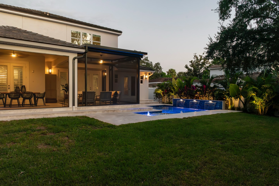 A luxurious backyard pool with waterfall features and an outdoor living area by Landscape-Fusion in Tampa, FL