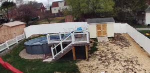 An aerial view of a comprehensive backyard renovation featuring a new deck, above-ground pool, shed, and white vinyl fence by Gold-Mine Construction, LLC in Pittsburgh, PA.