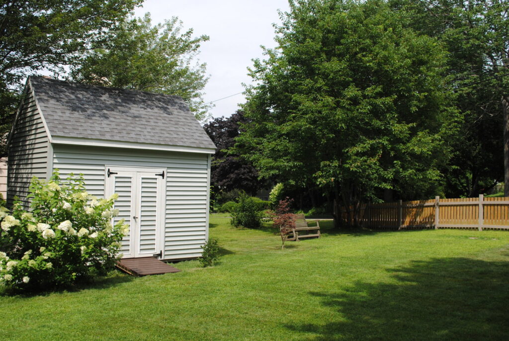 A well-built backyard shed on a green lawn, showcasing construction services by Casco Bay Construction Services, LLC in South Portland, ME.