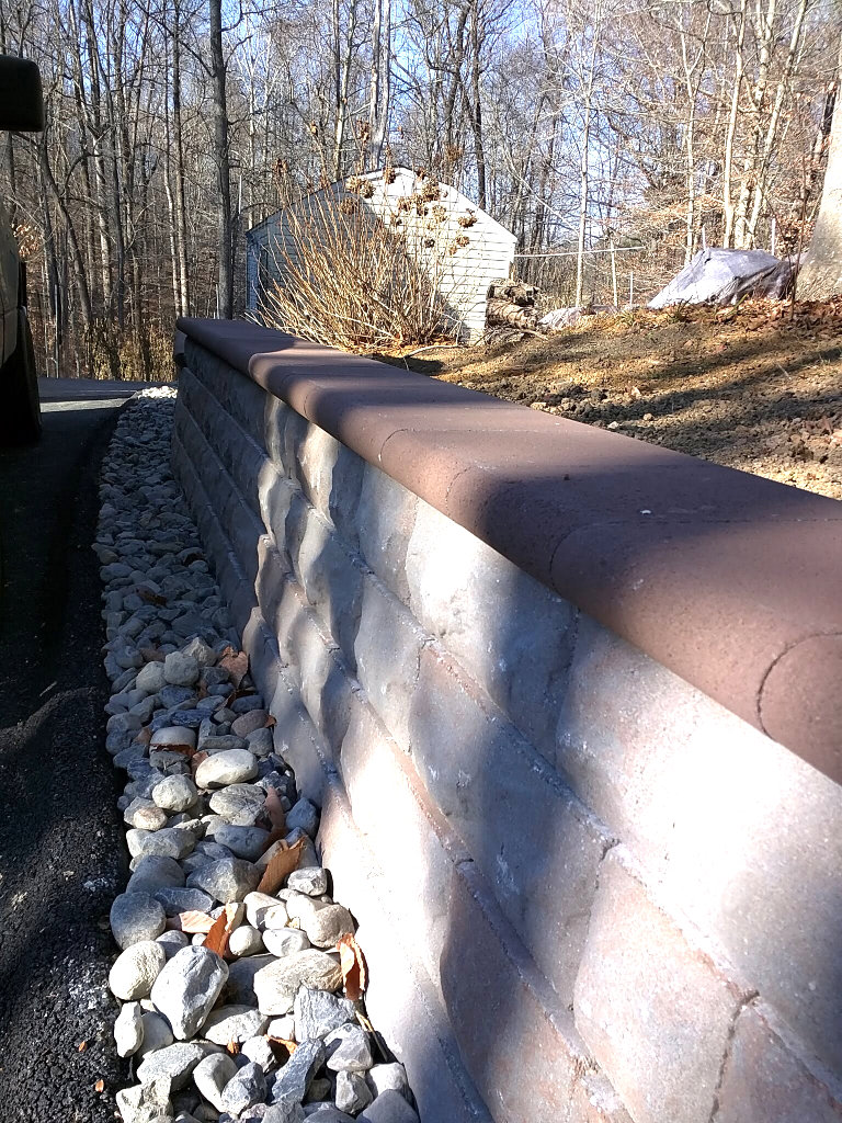 A sturdy stone retaining wall in a backyard, expertly built by Landscape By Today in Bowie, MD.