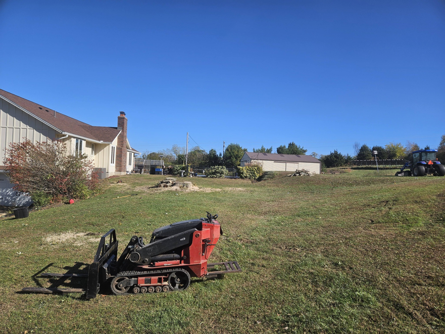 A backyard showing tree removal debris and a skid steer, indicating recent tree service work by Abbas' Arbor Care LLC in Kansas City, MO.