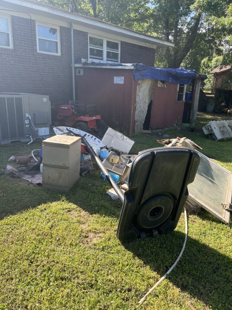 A backyard filled with large junk items and debris, including a basketball hoop and cabinet, for removal by LP Junk Removal in Birmingham, AL.