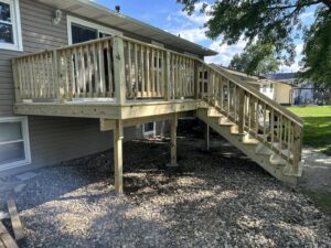 A spacious backyard wooden deck with matching railings and stairs, built by Watertown Handyman in Watertown, SD.