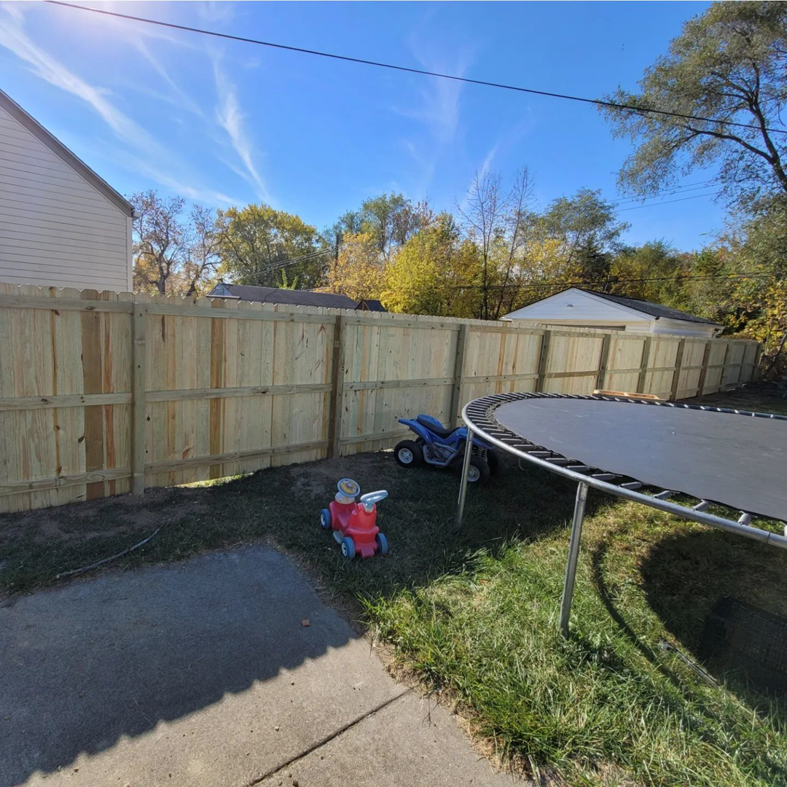 A long wooden fence installed in a residential backyard by Del Rey Properties LLC in Dearborn, MI.