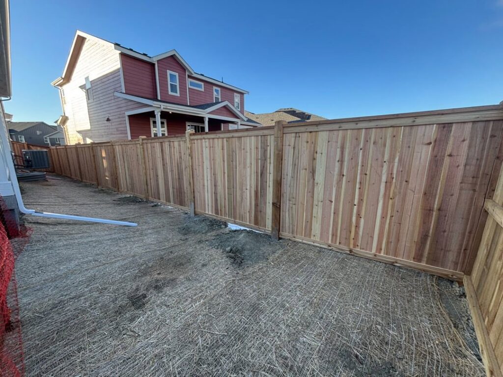A newly installed wooden privacy fence in a backyard by Blue Collar Service Pros in Aurora, CO.