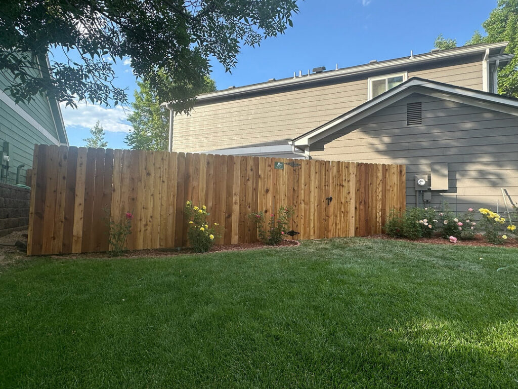 A backyard wooden privacy fence installation by GreenView Solutions in Denver, CO, with green lawn.