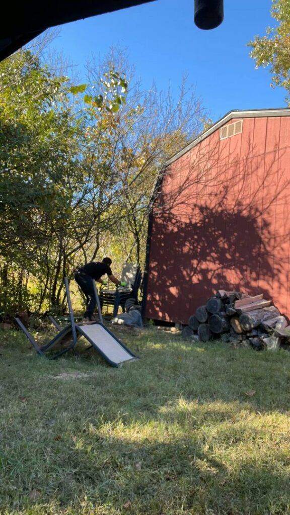 A Strong Lion Junk Removal team member performing a yard waste cleanout in a residential backyard in Fayetteville, AR.