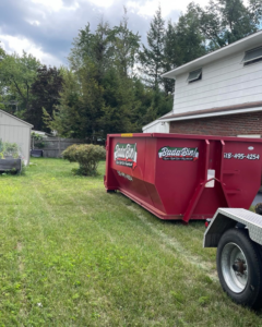A Bada Bin junk removal dumpster placed in a residential backyard for a cleanup project in Schenectady, NY.