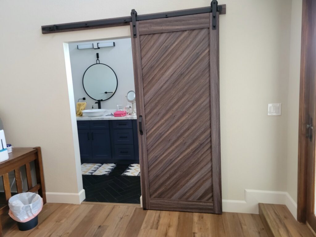 A newly installed barn door leading into a bathroom, completed by McCarran Handyman Services in Boulder City, NV.