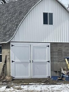 Newly installed white double barn doors on a building by S-Squared Construction in Madison, WI.