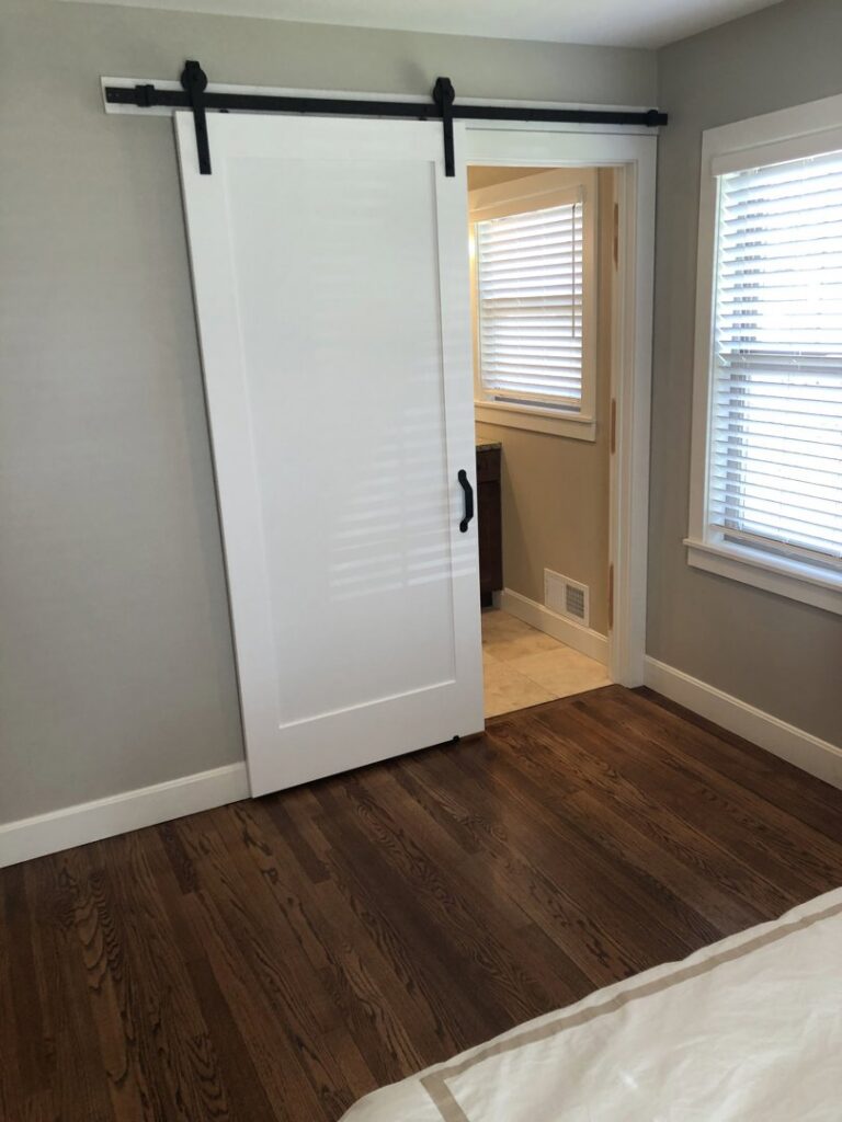 A newly installed white barn door leading to a bathroom, completed by Westlake Ace Handyman Services Kansas City Metro in Lenexa, KS.