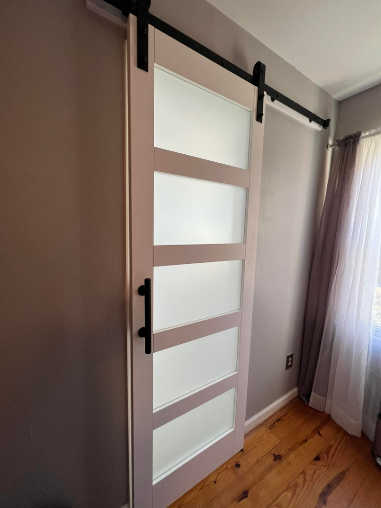 A newly installed modern barn door with frosted glass panels by Whitney Construction in Rockville, VA.