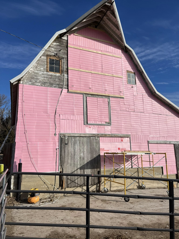 Barn siding installation in progress with pink insulation panels and scaffolding by CJP Construction handyman services in Pierce, NE.