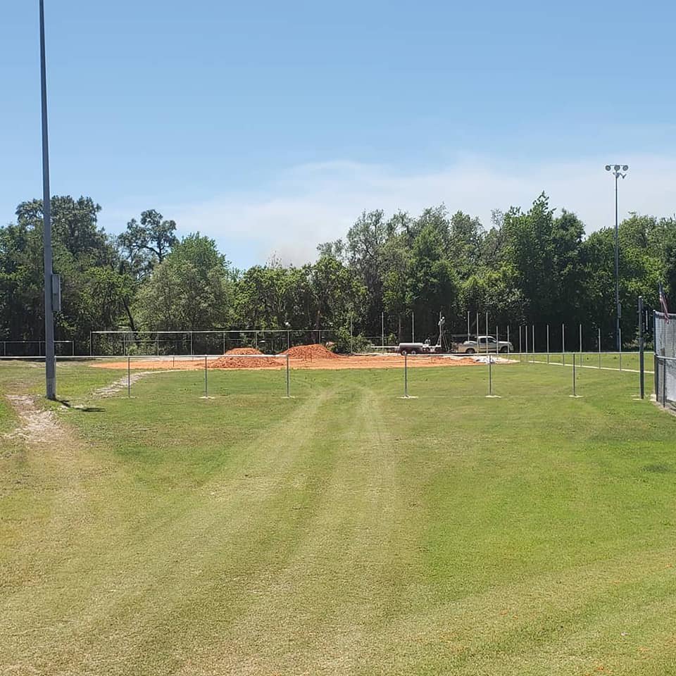 Baseball field showing new fence post installation and dirt piles by Keeler Fence in New Port Richey, FL.